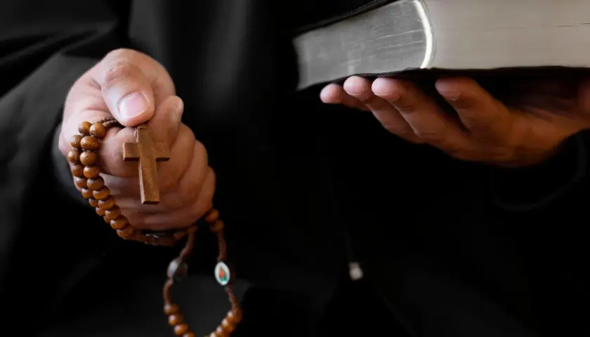 Ein Priester hält ein Rosenkranz und eine Bibel. Dies sind Werkzeuge, die bei einem Exorzismus verwendet werden, um böse Geister zu vertreiben.