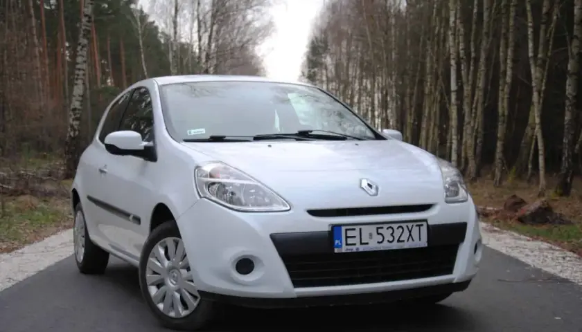 Biały Renault Clio 3 1.2 benzyna zaparkowany na leśnej drodze.