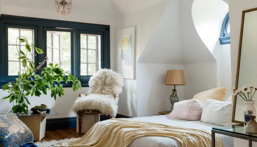 Cozy bedroom with a fluffy chair, yellow throw, and plants. Learn how to pick bedroom furniture for a stylish, inviting space.