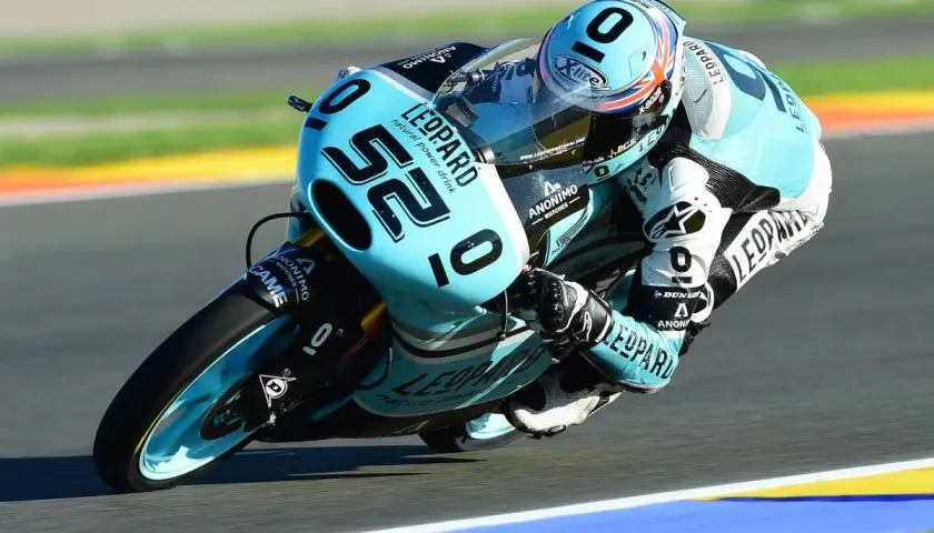 Danny Kent inclinado en su moto azul y negra, número 52, compitiendo en una carrera.