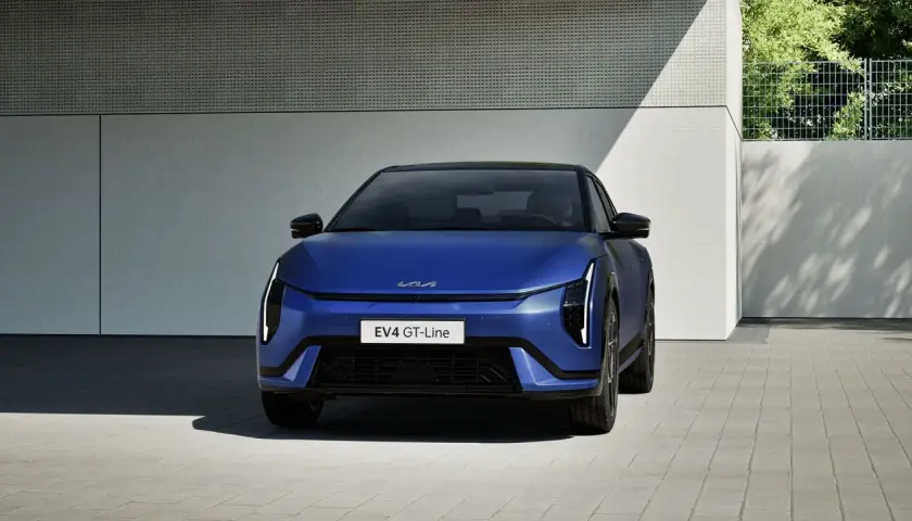 Niebieski Kia EV4 GT-Line, elektryczny sedan, prezentuje się nowocześnie przed budynkiem.