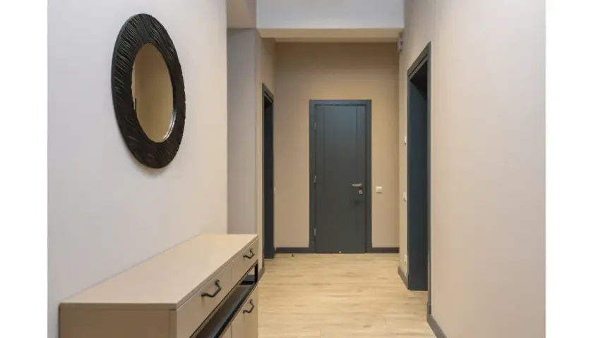 Un couloir sans fenêtre peut être lumineux avec des murs clairs et un grand miroir. Les portes sombres créent un contraste élégant.