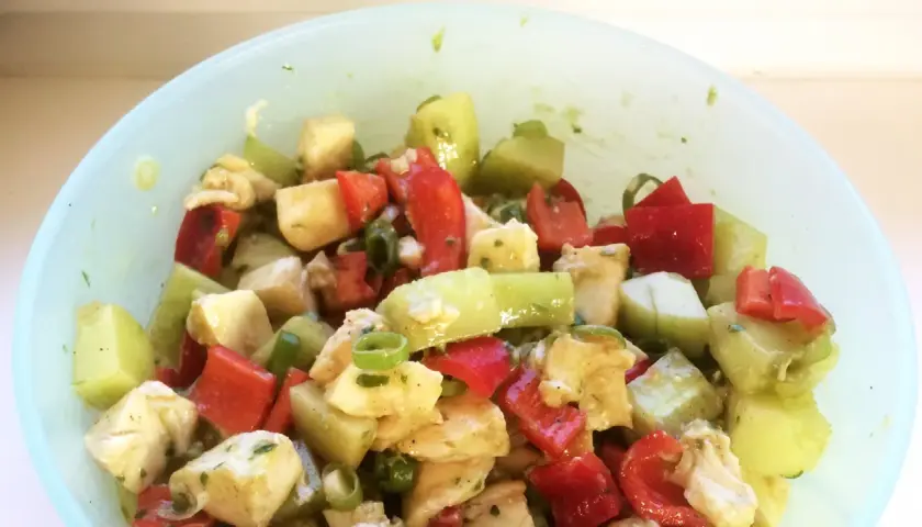 Frischer Salat mit gewürfeltem Gemüse und Käse, verfeinert mit Pesto.