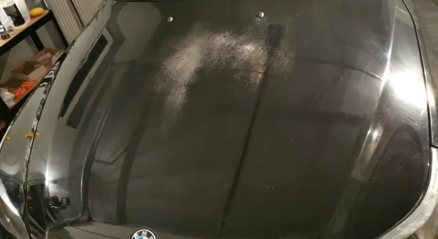 Na czarnej masce BMW widać liczne drobne rysy i zmatowienia, tworzące efekt "oczek na lakierze".