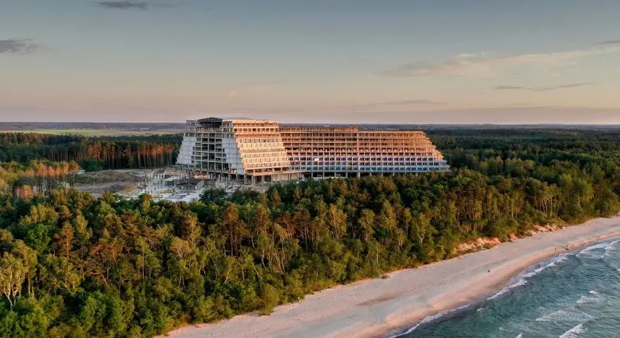 Ogromny, niedokończony hotel, który ma być największym hotelem w Polsce, góruje nad lasem i plażą o zachodzie słońca.