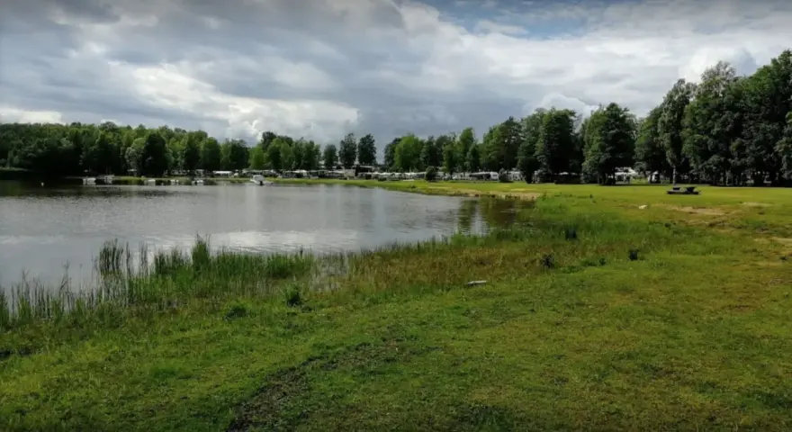 Vacker sjö vid Torsvikens camping med husbilar och träd.