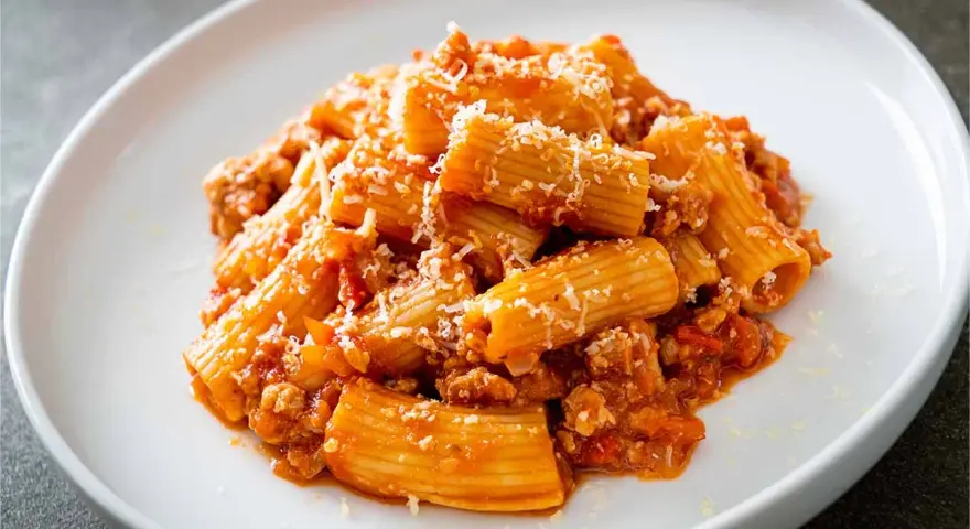 Un piatto invitante di pasta alla zozzona, con rigatoni conditi con un ricco ragù e abbondante parmigiano grattugiato.