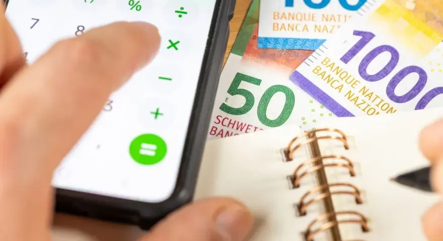 Rechnung für das Kostgeld der Kinder: Ein Handy mit Taschenrechner, Schweizer Franken und ein Notizbuch.