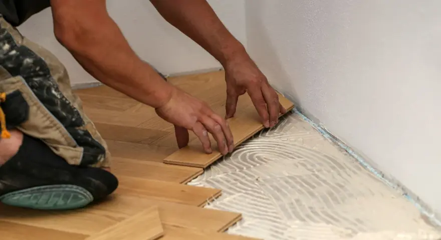 Manos colocando tablones de madera para un piso de parquet. Calculando el precio parquet piso 70m2.