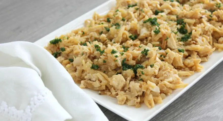 Delicioso plato de migas de bacalao desmenuzado, salteado y espolvoreado con perejil fresco.