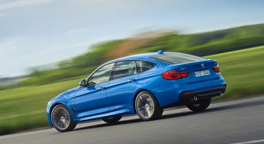 Niebieskie BMW 3 GT w ruchu, ukazujące jego sportowy profil. Warto rozważyć jego wady i zalety przed zakupem.