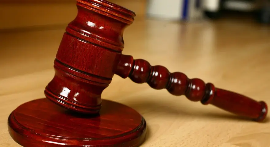 Młotek sędziowski na drewnianym stole. Symbolizuje sprzedaż mieszkania z wpisem komorniczym i decyzje prawne.
