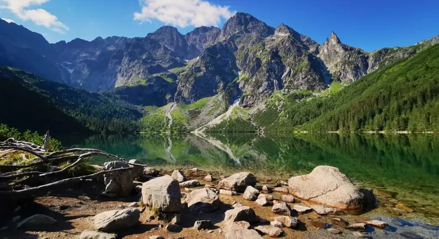 Kamienista plaża nad Morskim Okiem. W tle majestatyczne szczyty Tatrzańskiego Parku Narodowego odbijają się w krystalicznie czystej wodzie.