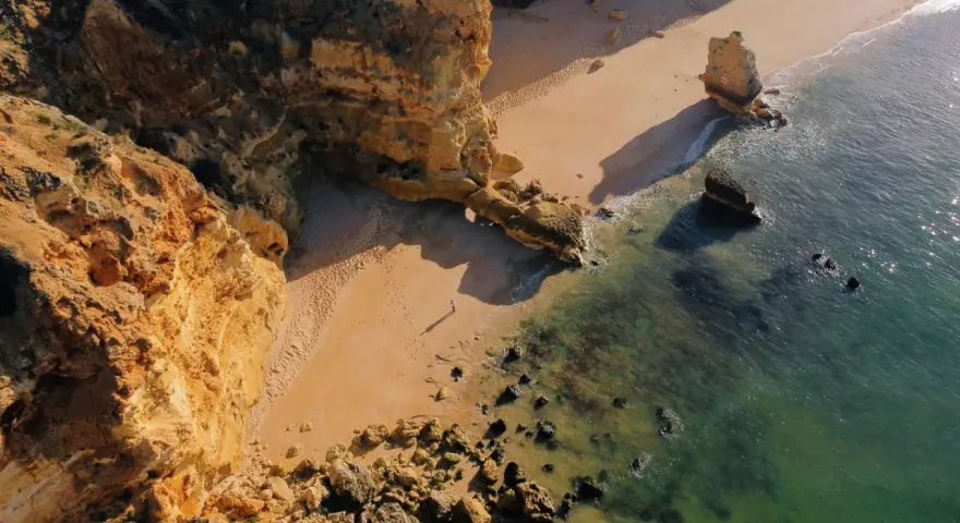 Malownicze klify i piaszczysta plaża w Portugalii. Morze o turkusowym odcieniu obmywa skaliste wybrzeże, tworząc idealne miejsce na spacer.