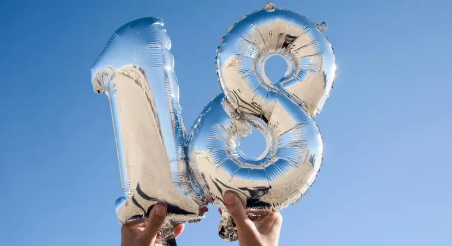 Silberne Folienballons in Form der Zahl 18 vor blauem Himmel.
