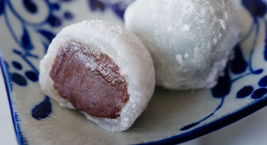Pyszne mochi z czekoladowym nadzieniem, posypane cukrem pudrem. Idealne do domowego przepisu na mochi.