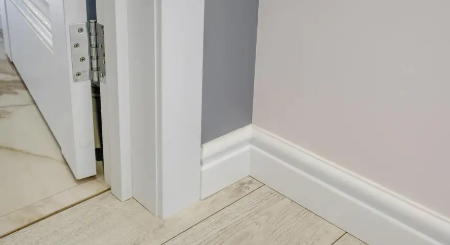 Nymålade vita snickerier runt en dörröppning och längs väggen ger ett fräscht intryck.