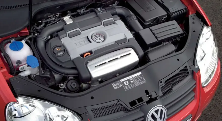 Silnik 1.4 TSI Twincharger w czerwonym Volkswagenie. Widoczne elementy układu dolotowego i chłodzenia.