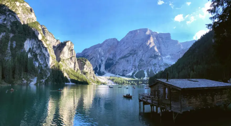 Malownicze jezioro w Dolomitach, z górami w tle i drewnianym domkiem na wodzie. Idealne miejsce na camping i podziwianie natury.