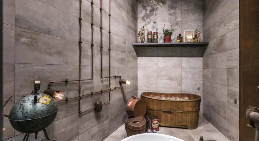 Ambiance unique dans cette salle de bain industrielle avec baignoire en bois, tuyauterie apparente et lampes vintage.