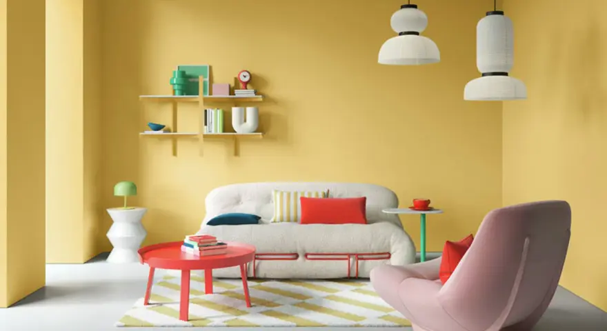 Lebendige wohnraumgestaltung farben: gelbe Wände, ein flauschiges Sofa, ein roter Couchtisch und ein rosa Sessel schaffen eine fröhliche Atmosphäre.