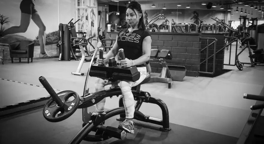 Kvinna tränar sittande vadpress på gym.