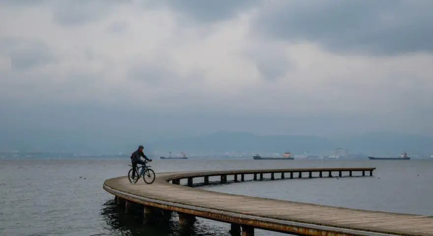 Rowerzysta przemierza malownicze trasy rowerowe nad morzem, podziwiając spokojną taflę wody i statki na horyzoncie.