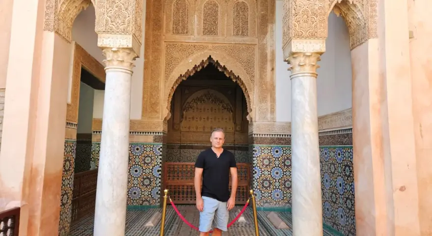 Hombre posa ante intrincada arquitectura marroquí. ¡Ideas para que ver en Marrakech en 2 días!