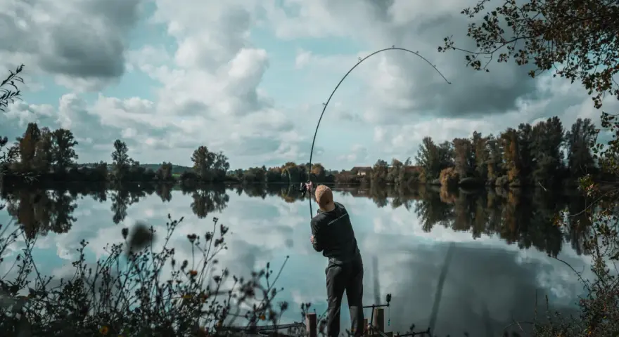 Wędkarz na pomoście, zgięta w łuk wędka świadczy o walce z rybą. Konopie na ryby to jego pasja.