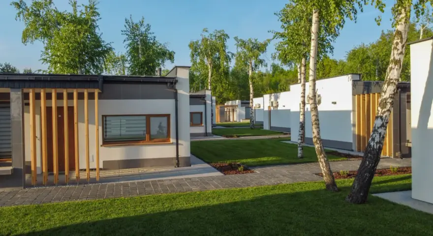 Nowoczesne domki na riviera camp otoczone zielenią i drzewami.