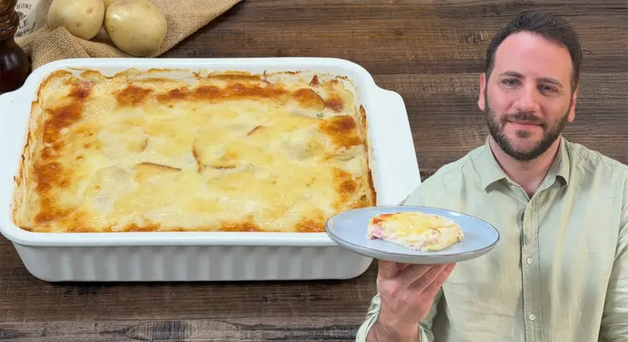 Un uomo sorride mostrando una fetta di parmigiana di patate appena sfornata, dorata e filante.