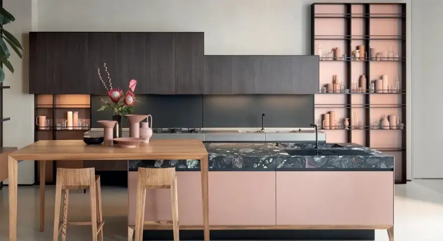 Cucina moderna con isola rosa cipria e piano in pietra scura, pensili in legno scuro. Ottimi abbinamenti colori cucine moderne.