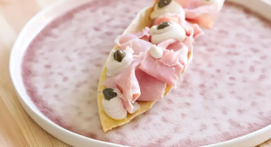 Delizioso antipasto con pane carasau, prosciutto cotto, crema e capperi. Un'idea per ricette veloci e gustose.