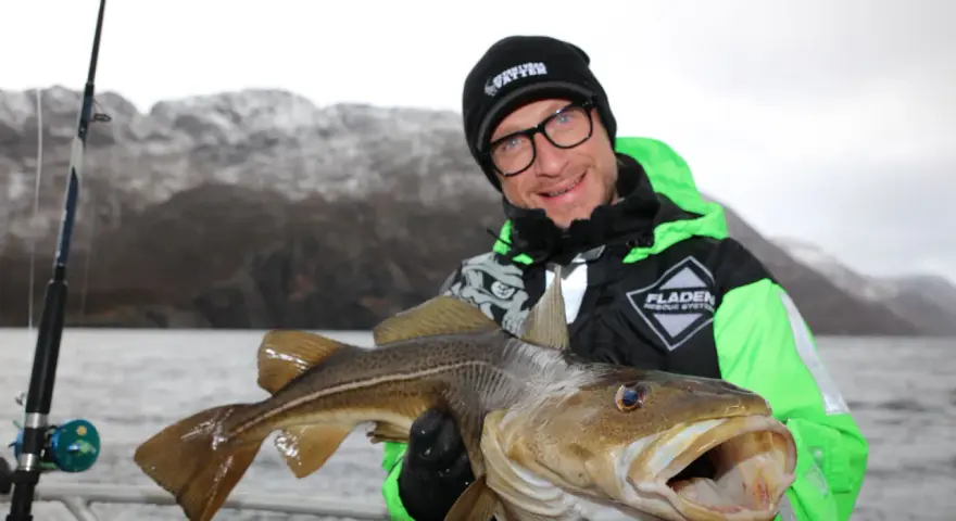 Glad fiskare visar upp en stor torsk fångad i Norge.