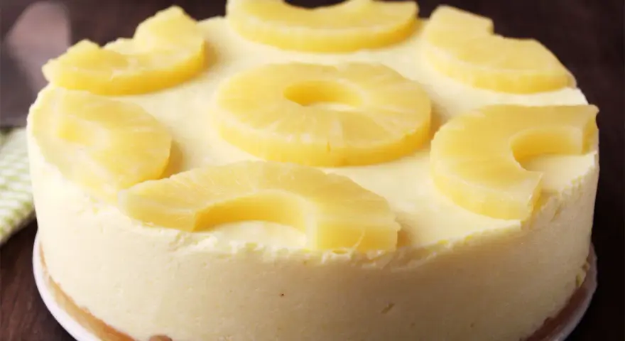 Tarta de piña cremosa, decorada con rodajas y trozos de piña fresca. ¡Un postre tropical irresistible!
