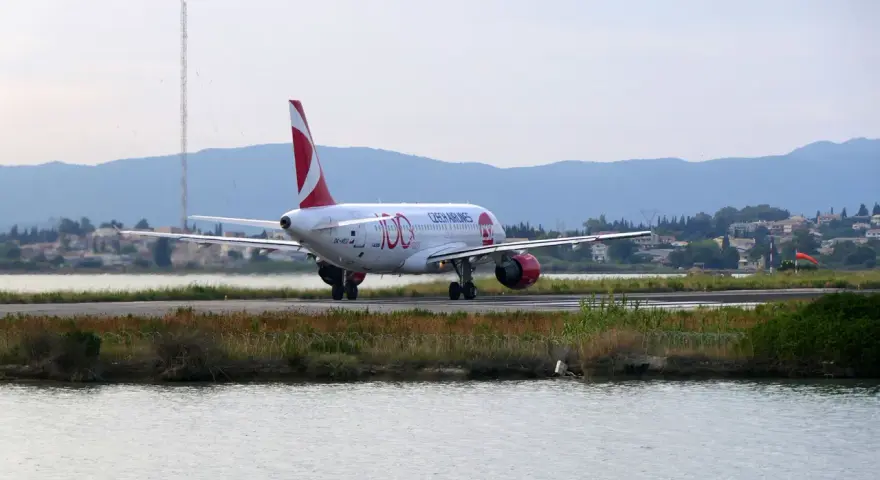 Samolot Czech Airlines na pasie startowym lotniska na Korfu, z wodą i zielenią w tle.