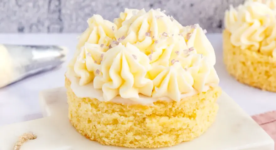 Kleiner Kuchen mit Buttercreme ohne Pudding, verziert mit lila Zuckerstreuseln.