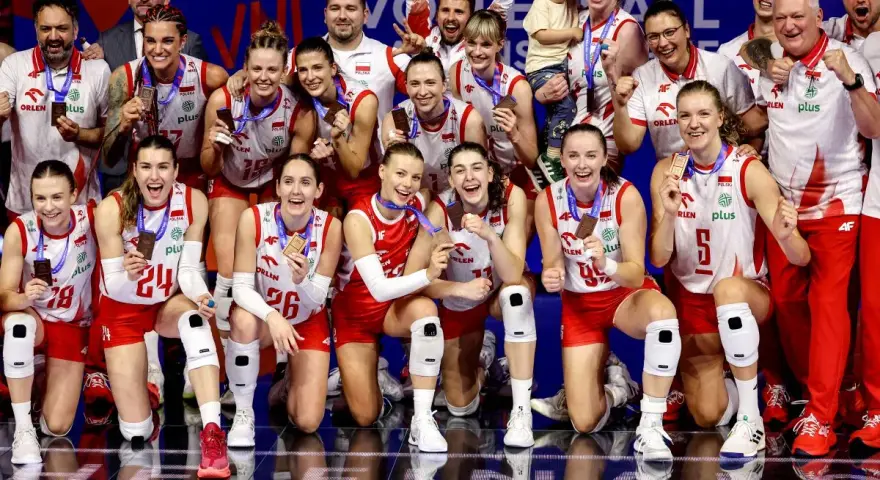 Drużyna siatkówki kobiet Polska świętuje sukces w Lidze Narodów. Zawodniczki z medalami na szyjach i uśmiechami na twarzach.