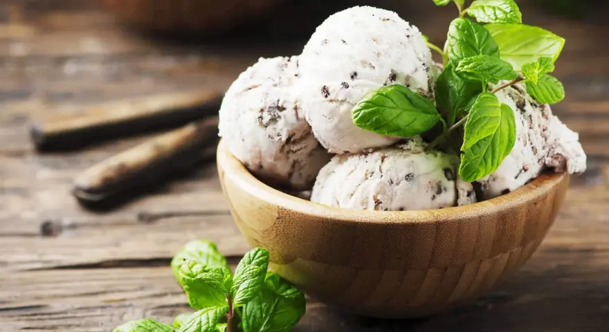 Schüssel mit Stracciatella Eis und frischer Minze auf Holzhintergrund.