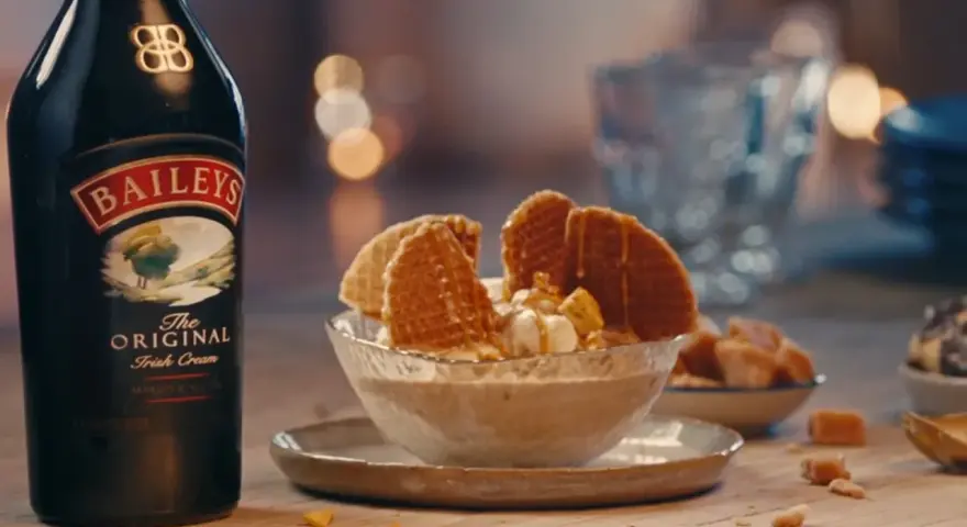 Baileys Eis Rezept: Cremiges Eis mit Karamell und Waffeln, daneben eine Flasche Baileys.