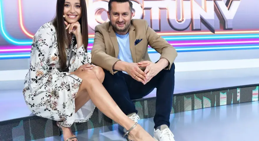 Uśmiechnięta para na planie "Koło Fortuny kto ubiera". Ona w kwiecistej sukience i sandałkach, on w marynarce i jeansach.