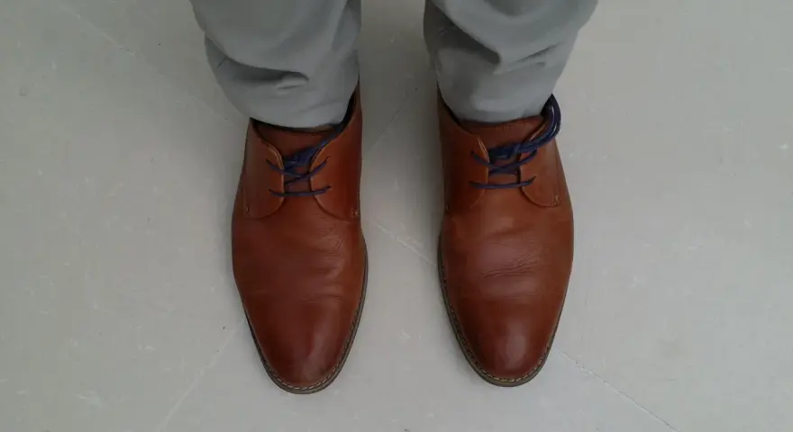 Scarpe marroni eleganti con lacci blu nascosti, un modo per allacciare le scarpe senza far vedere i lacci.