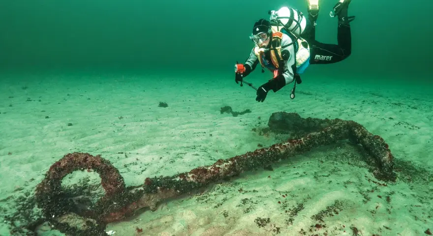 Taucher erkundet ein altes Ankerwrack in der Ostsee.