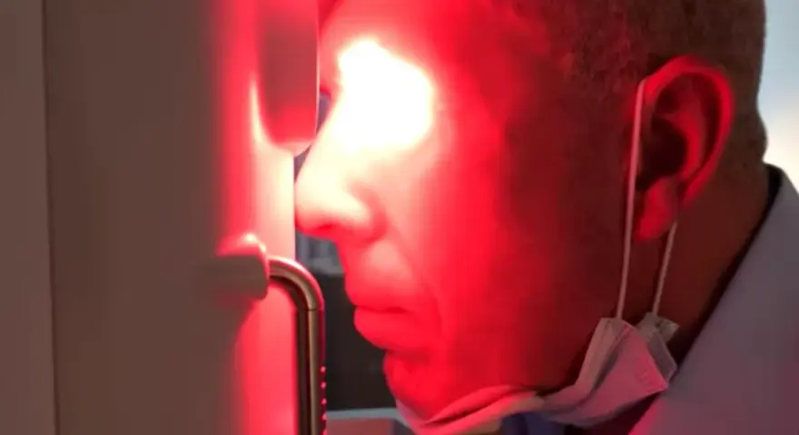 Uomo con maschera chirurgica sotto il mento, riceve fotobiomodulazione facciale. Attenzione alle fotobiomodulazione controindicazioni.