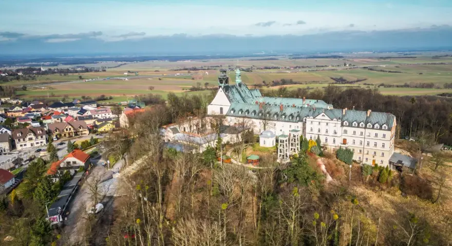 Widok z lotu ptaka na klasztor na świętej górze, otoczony lasem i miasteczkiem.