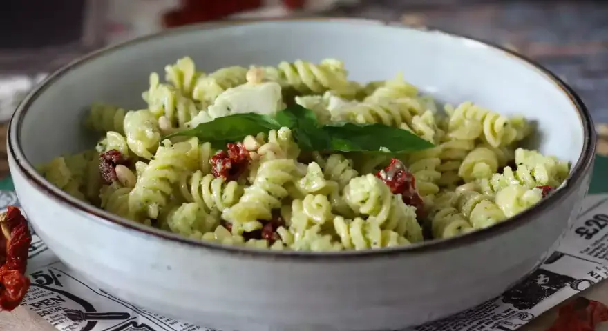 Fusilli con pesto, pomodori secchi, pinoli e basilico fresco. Un piatto di pasta con verdure colorato e saporito.