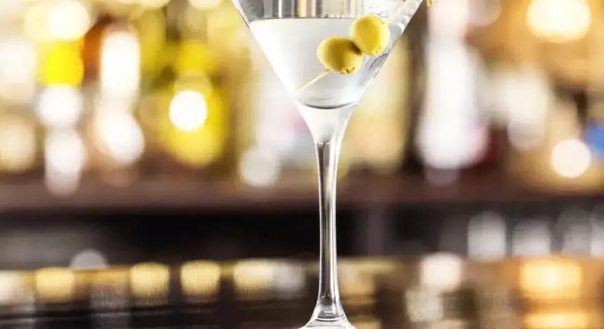 Klasyczny martini dry przepis: schłodzony gin, odrobina wermutu i dwie oliwki. Idealny drink na wieczór.