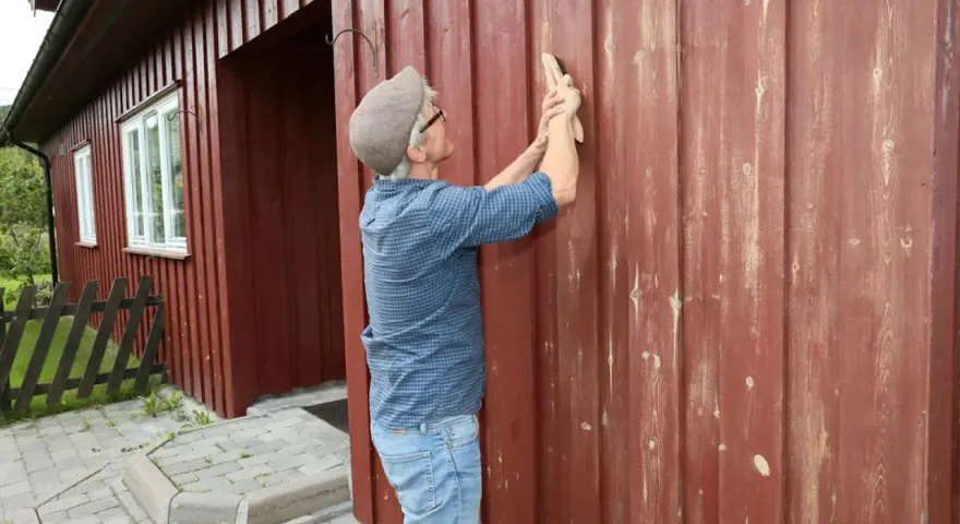 Man slipar fasaden innan målning.