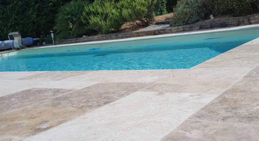 Le travertin autour de la piscine crée une terrasse naturelle et élégante, invitant à la détente sous le soleil.