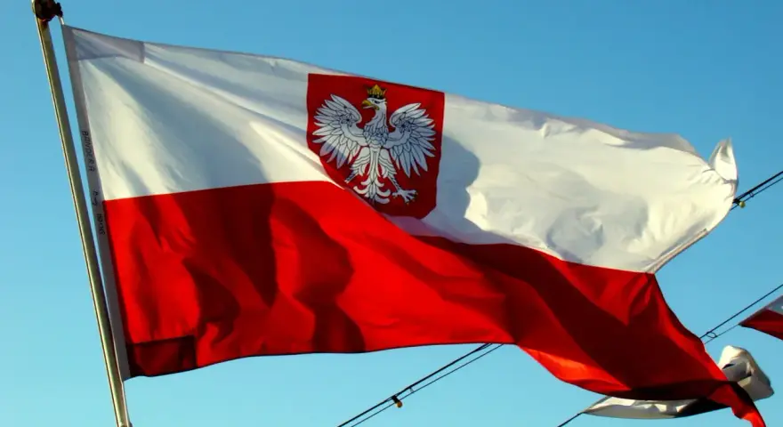 Polska bandera z orłem na tle błękitnego nieba. To symbol dumy narodowej, który powiewa na wietrze.